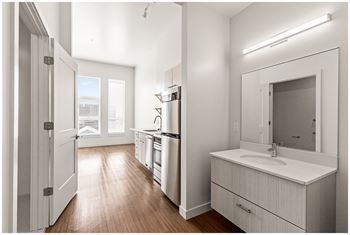 A modern kitchen with white cabinets and a wooden floor. at RiDE at RiNo Apartments, Denver 80216